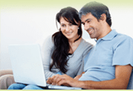 A man and woman sitting in front of a laptop.