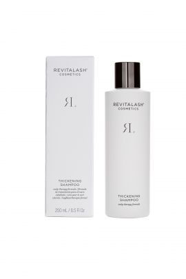 A bottle of revitlash cleansing milk sitting next to its box.